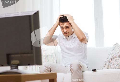 Image of disappointed man watching tv at home