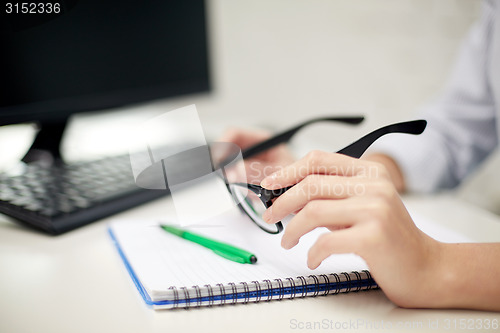 Image of close up of hands with eyeglasses and notebook