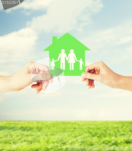 Image of hands holding green house with family