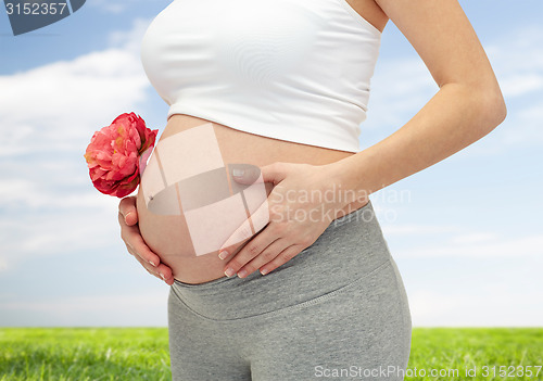 Image of close up of pregnant woman touching her bare tummy