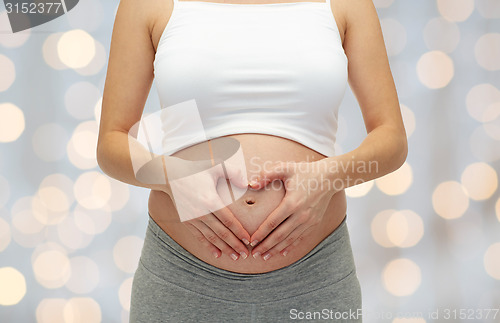 Image of close up of pregnant woman touching her bare tummy