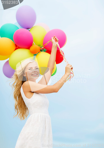 Image of smiling woman with colorful balloons outside