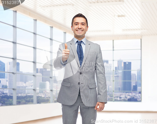 Image of happy businessman in suit showing thumbs up