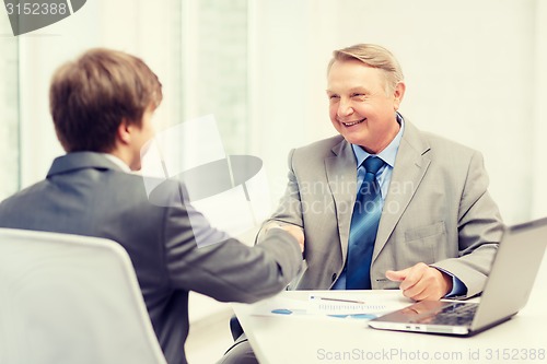 Image of older man and young man shaking hands in office