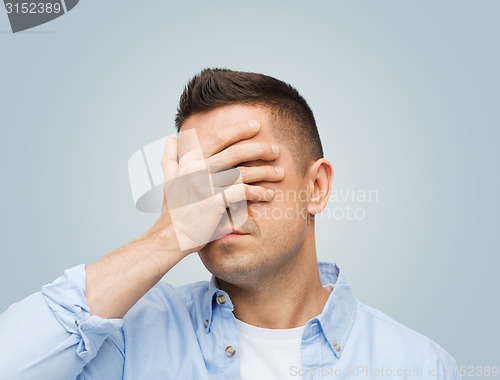 Image of unhappy man covering his eyes by hand