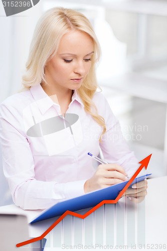 Image of businesswoman writing to clipboard in office