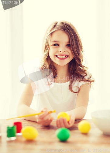 Image of smiling little girl coloring eggs for easter