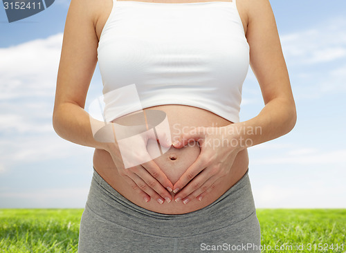 Image of close up of pregnant woman touching her bare tummy