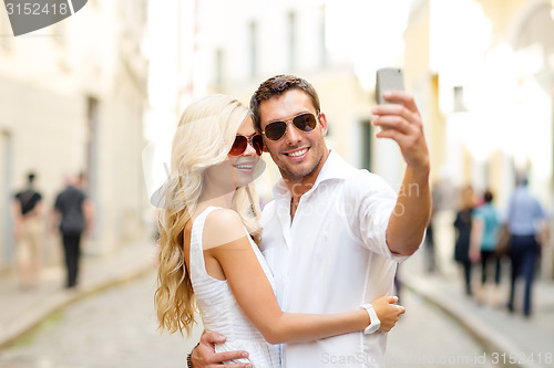 Image of smiling couple with smartphone in the city