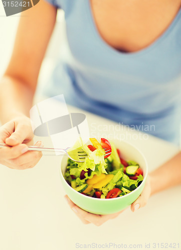 Image of woman eating salad with vegetables
