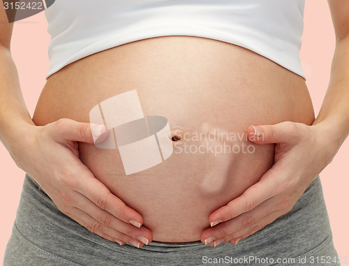 Image of close up of pregnant woman touching her bare tummy