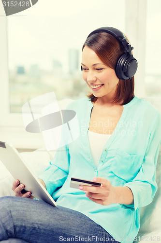 Image of happy woman with tablet pc and credit card at home