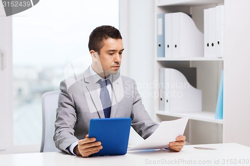 Image of businessman with tablet pc and papers in office