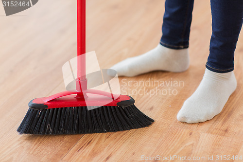 Image of close up of woman legs with broom sweeping floor