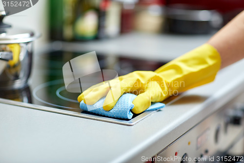 Image of close up of woman cleaning cooker at home kitchen