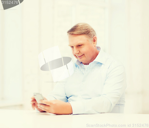 Image of old man at home with smartphone
