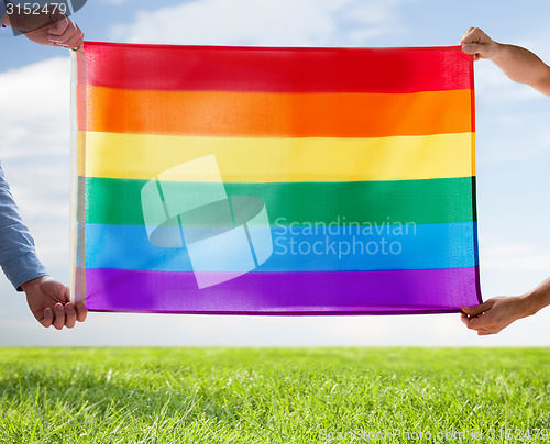 Image of close up of male gay couple holding rainbow flag