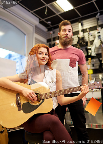 Image of couple of musicians with guitar at music store