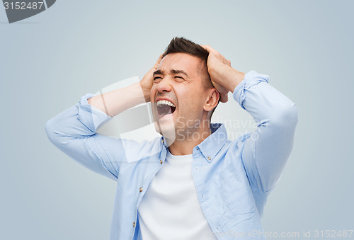 Image of unhappy man with touching his head and screaming