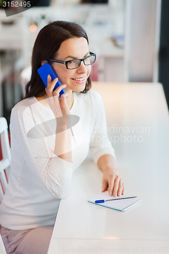 Image of smiling woman calling on smartphone at cafe