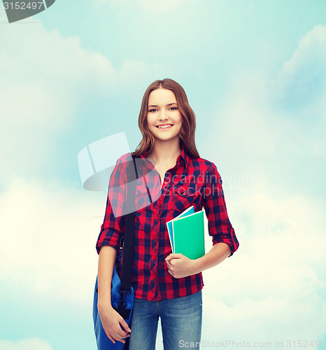 Image of smiling female student with bag and notebooks