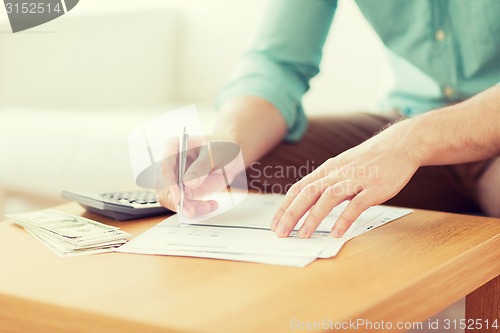 Image of close up of man counting money and making notes