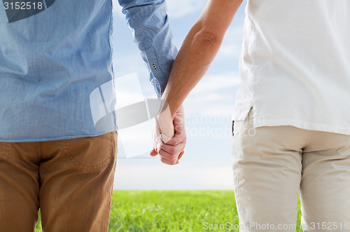 Image of close up of happy male gay couple holding hands