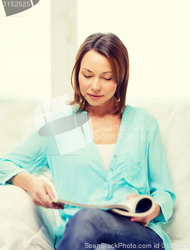 Image of smiling woman reading magazine at home