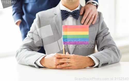 Image of close up of male gay couple holding rainbow flag