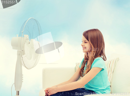 Image of smiling little girl with big fan at home