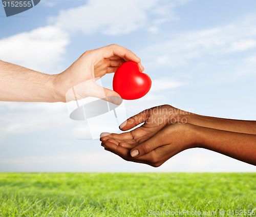 Image of woman and man hands with red heart