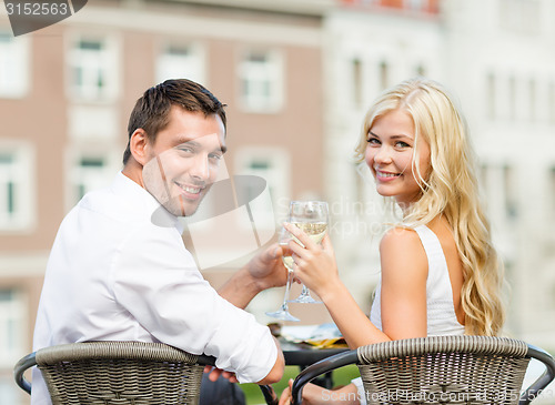 Image of smiling couple drinking wine in cafe