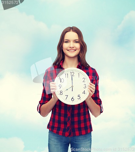 Image of young woman in casual clothes with wall clock