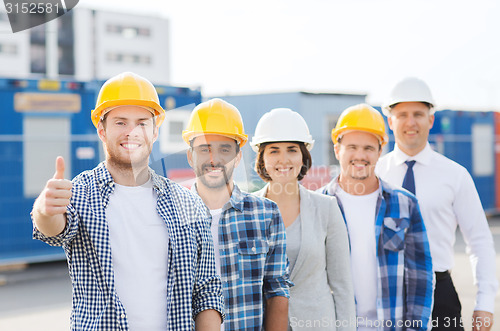 Image of group of smiling builders in hardhats outdoors