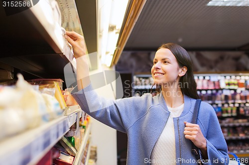 Image of happy woman choosing and buying food in market