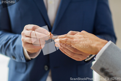 Image of close up of male gay couple hands and wedding ring