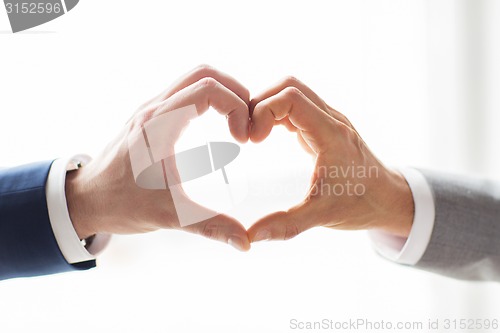 Image of close up of male gay couple hands showing heart