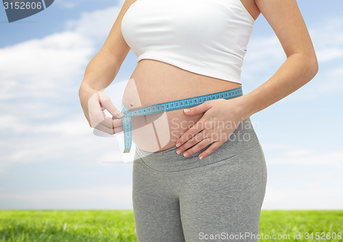Image of close up of pregnant woman measuring her tummy