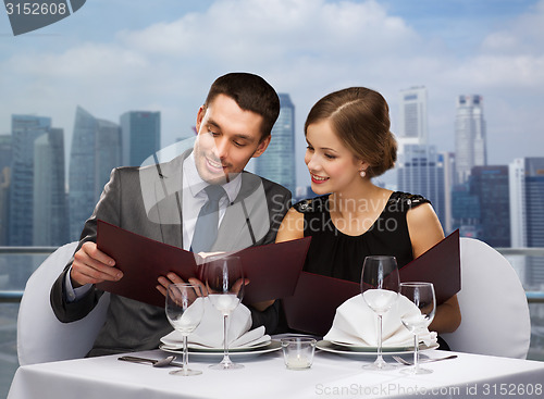 Image of smiling couple with menus at restaurant