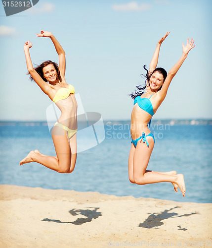 Image of girls in bikini jumping on the beach