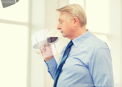 Image of older man smelling red wine