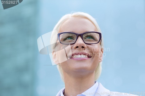 Image of young smiling businesswoman over office building