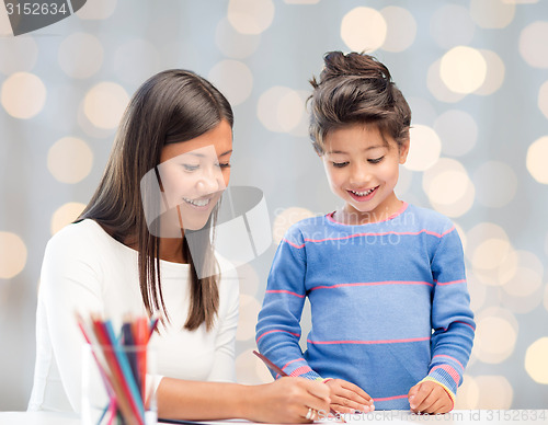 Image of happy mother and daughter drawing with pencils