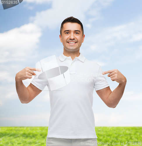 Image of smiling man in t-shirt pointing fingers on himself