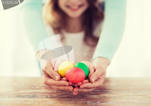 Image of close up of girl and mother holding colored eggs