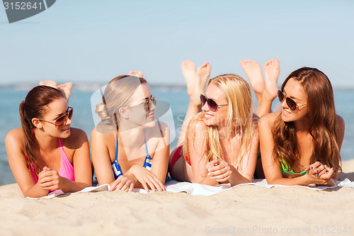 Image of group of smiling women in sunglasses on beach