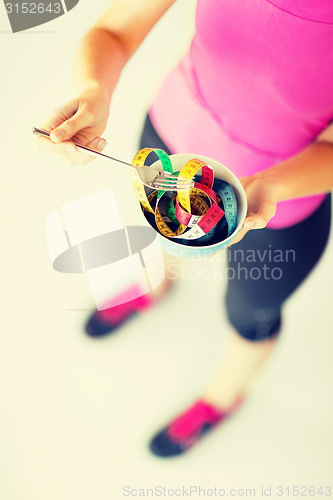 Image of woman hands holding bowl with measuring tape