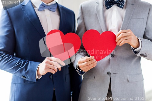 Image of close up of male gay couple holding red hearts