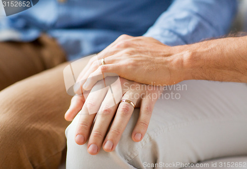 Image of close up of happy male gay couple holding hands