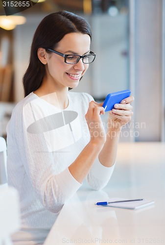 Image of smiling woman with smartphone at cafe